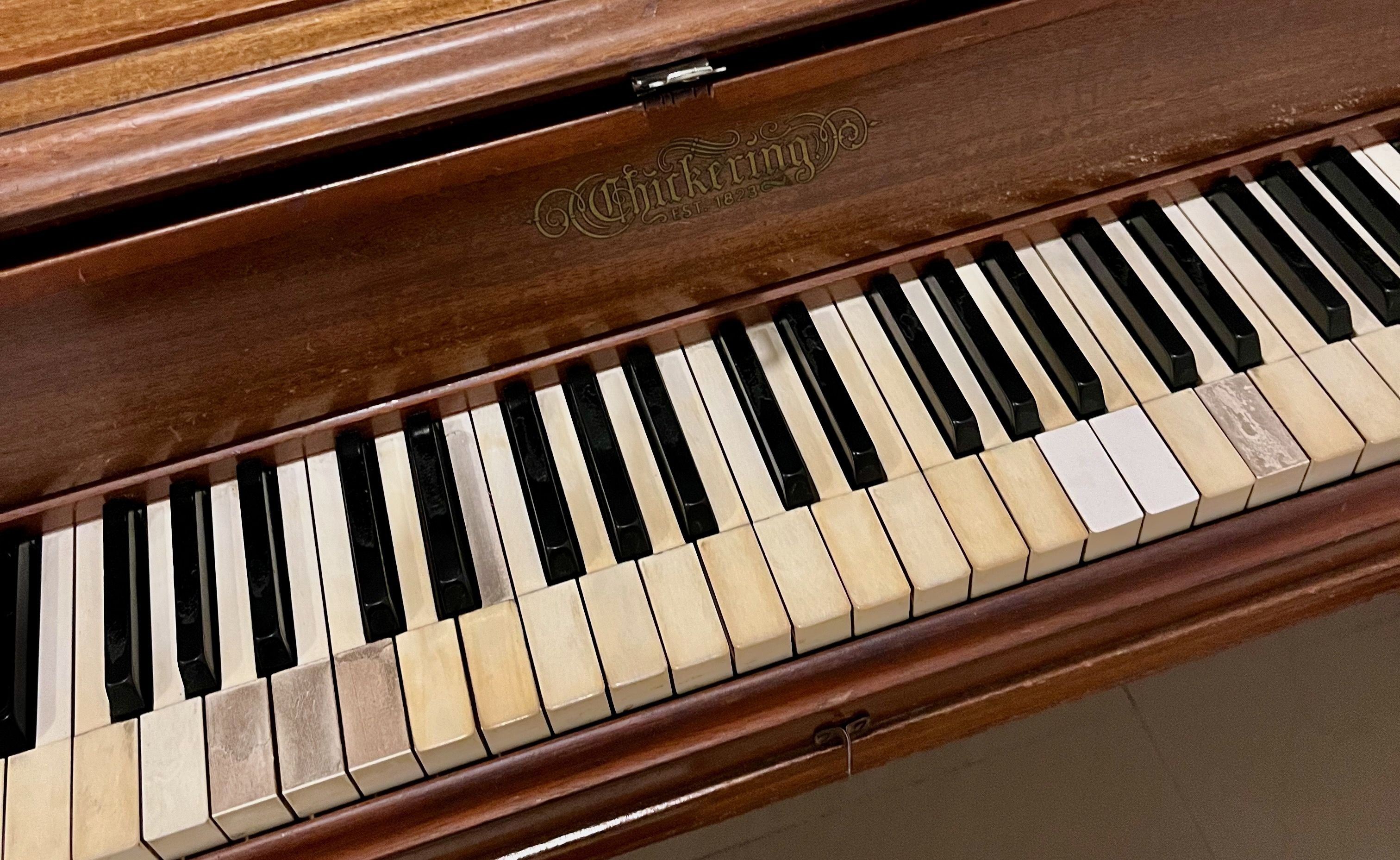 An upright piano with old keys and string out of tune