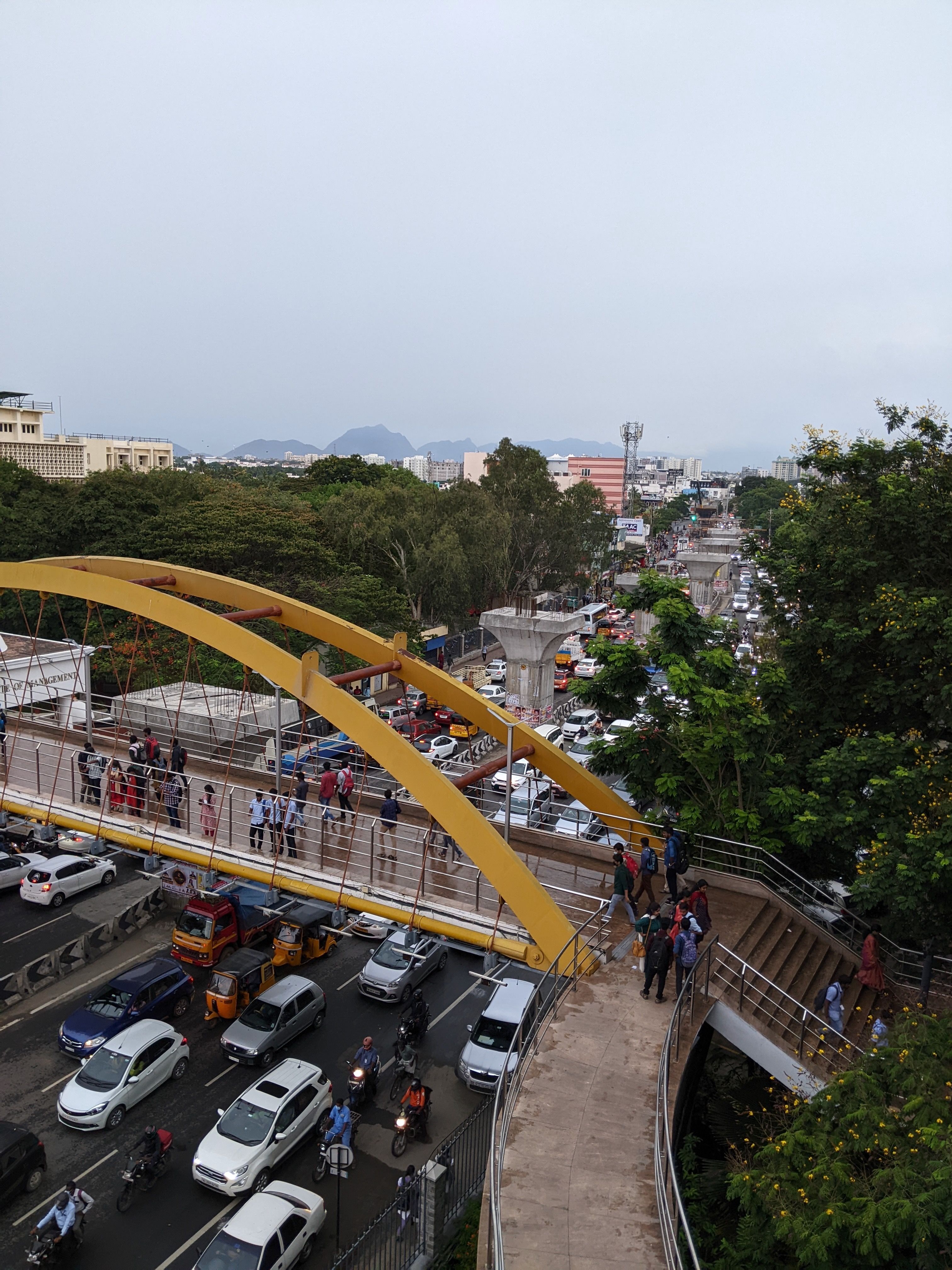 A bridge connecting two sides of a college separated by a highway full of traffic